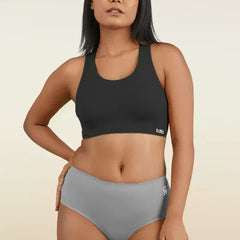 Woman wearing a black sports bra and gray mid-waist underwear on a beige background