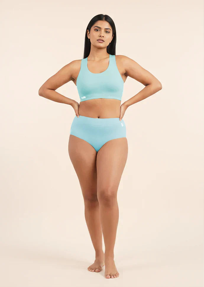 Woman wearing a blue bra and underwear set on a beige background