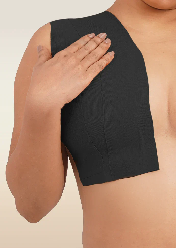 Person wearing a black boob tape on a beige background