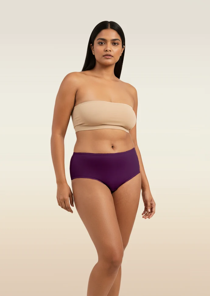 Woman wearing a beige strapless top and violet mid-waist underwear on a beige background