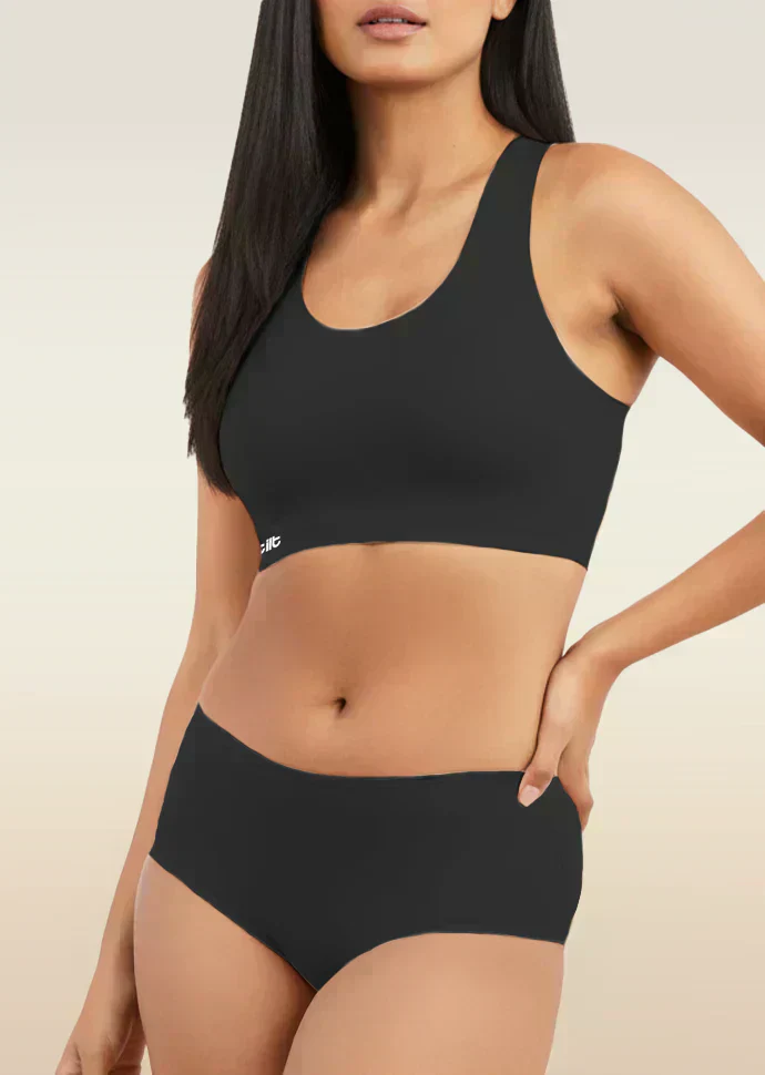 Woman wearing a black sports bra and mid-waist underwear set on a beige background