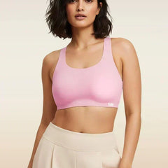 Woman wearing a pink sports bra and beige pants on a beige background
