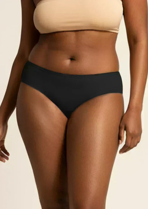 Person wearing black underwear and beige bra on a neutral background