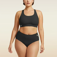 Woman wearing a black bra and  underwear set on a beige background
