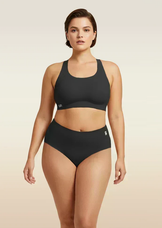 Woman wearing a black bra and  underwear set on a beige background