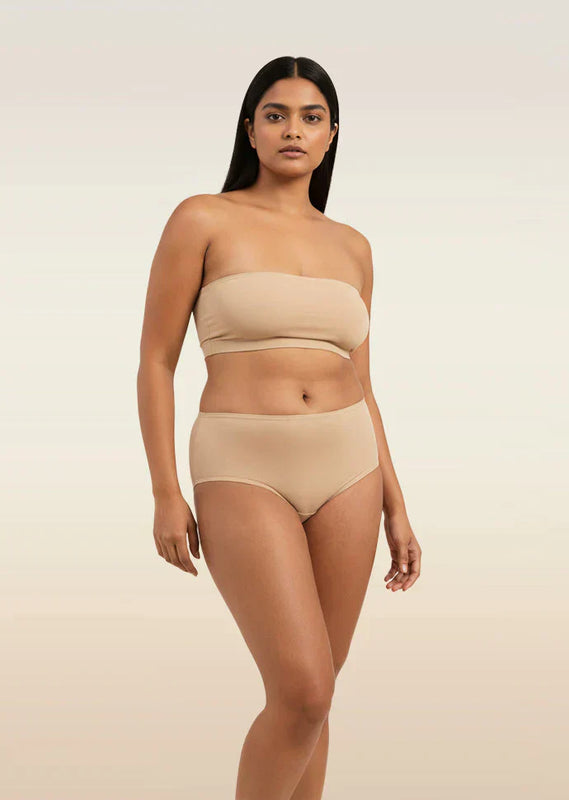 Woman wearing a beige strapless top and mid-waist underwear on a beige background