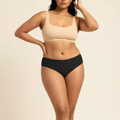 Woman wearing a beige sports bra and black low-waist bikini on a beige background