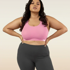 Woman wearing a pink sports bra and gray leggings on a beige background