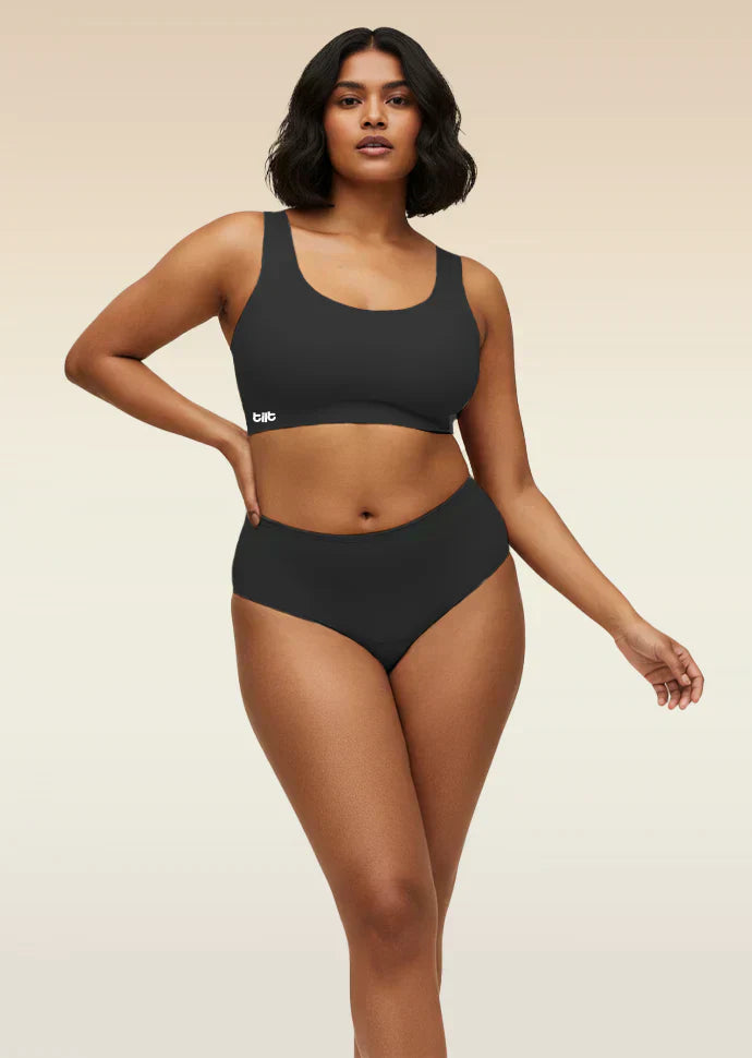 Woman wearing a black bra and  underwear set with a beige background