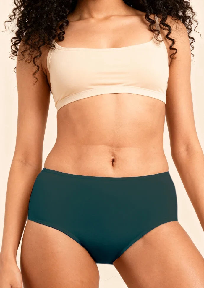 Person wearing a beige sports bra and teal mid-waist underwear on a neutral background