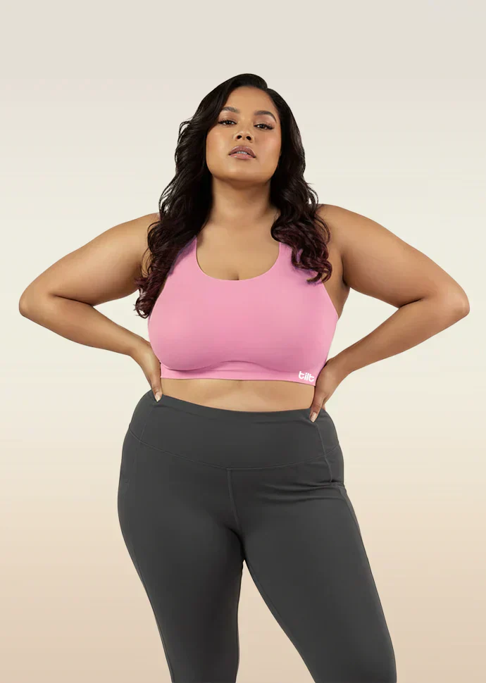 Woman wearing a pink sports bra and gray leggings on a beige background