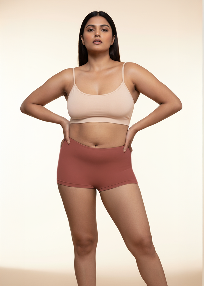 Woman wearing a beige bra and red mid-waist boyshorts on a beige background