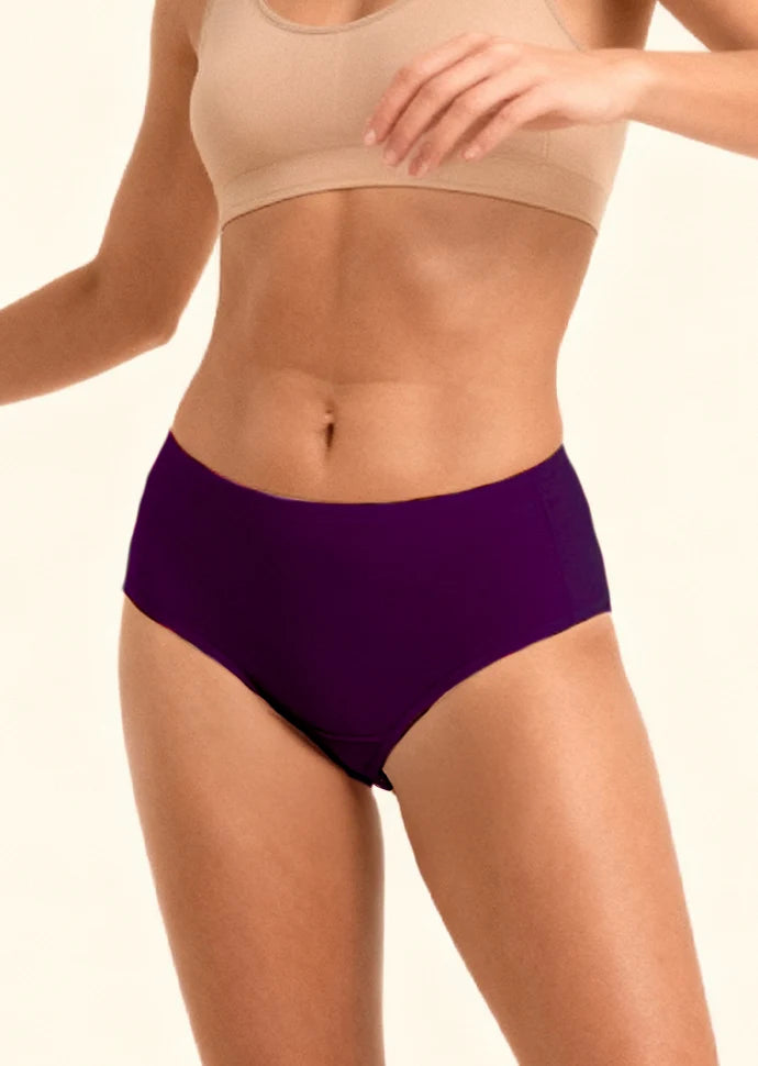 Person wearing a beige sports bra and violet mid-waist underwear  on a plain background