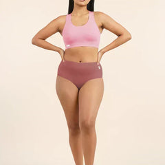 Woman wearing a pink sports bra and  pink mid-waist underwear on a beige background