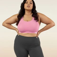 Woman wearing a pink sports bra and gray leggings on a beige background
