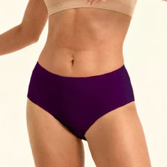 Person wearing a beige sports bra and violet mid-waist underwear  on a plain background