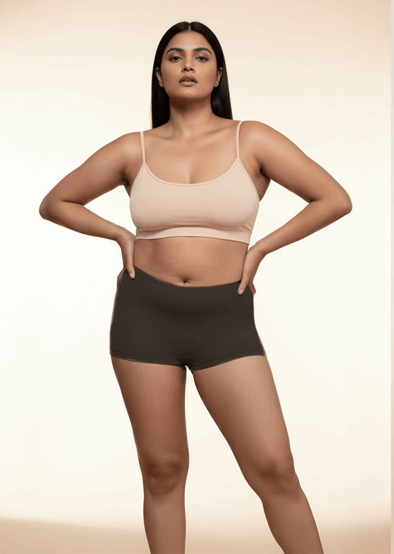 Woman wearing a beige bra and black boyshorts on a beige background