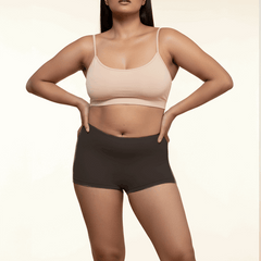 Woman wearing a beige bra and black boyshorts on a beige background