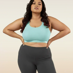 Woman wearing a blue sports bra and dark gray leggings on a beige background