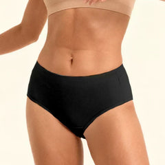 Person wearing black mid-waisted underwear and beige sports bra on a plain background