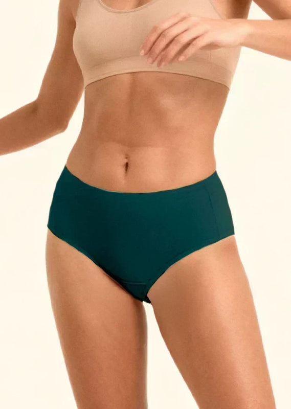 Person wearing teal mid-waist  underwear and beige sports bra on a plain background
