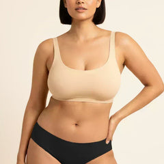 Woman wearing a beige bra and black underwear on a beige background