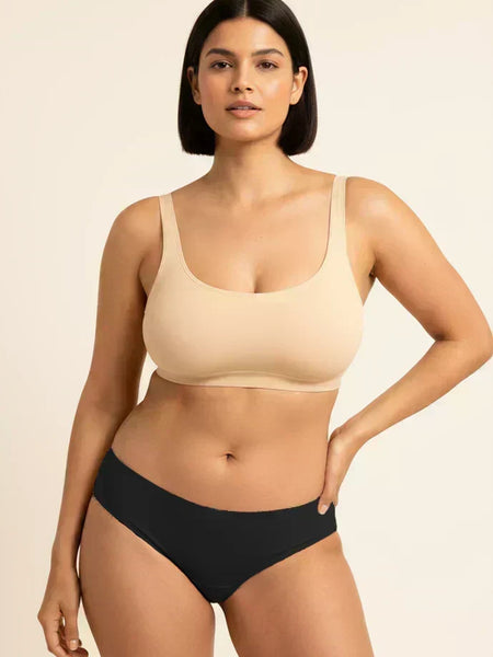 Woman wearing a beige bra and black underwear on a beige background