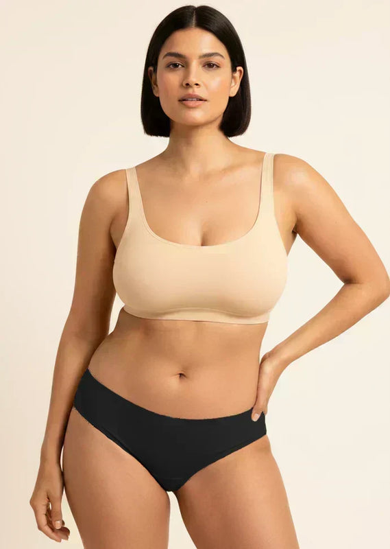 Woman wearing a beige bra and black underwear on a beige background