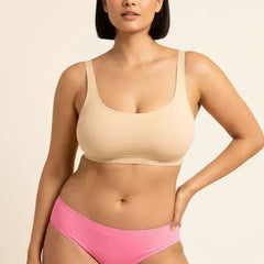 Woman wearing a beige bra and pink underwear on a beige background