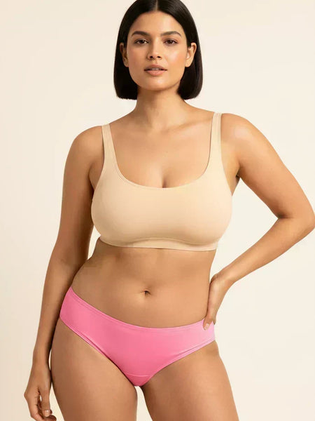 Woman wearing a beige bra and pink underwear on a beige background