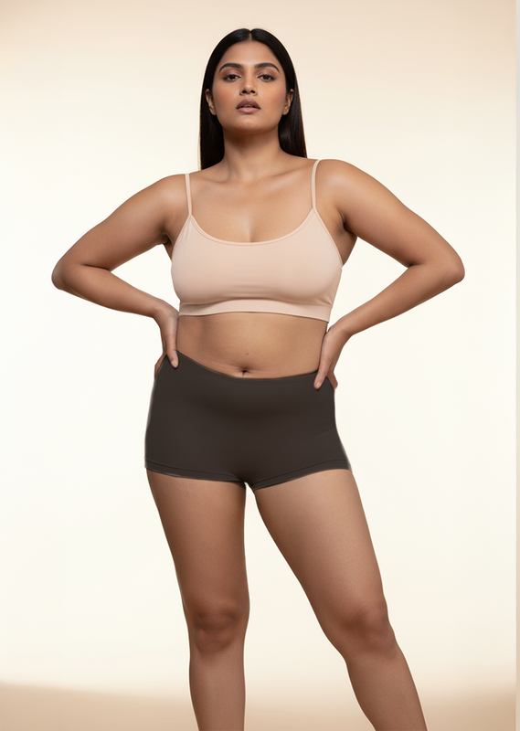 Woman wearing a beige bra and black boyshorts on a beige background