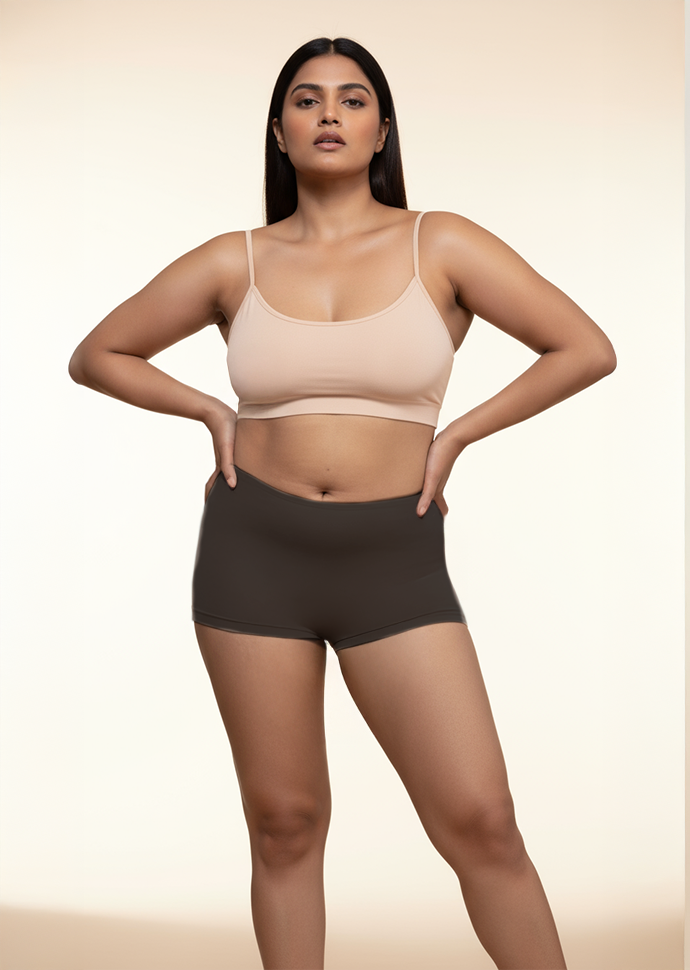 Woman wearing a beige bra and black boyshorts on a beige background