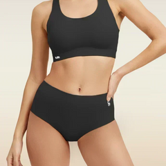 Woman wearing a black bra and  underwear set on a beige background