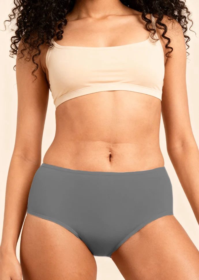 Person wearing a beige bra and gray underwear on a beige background