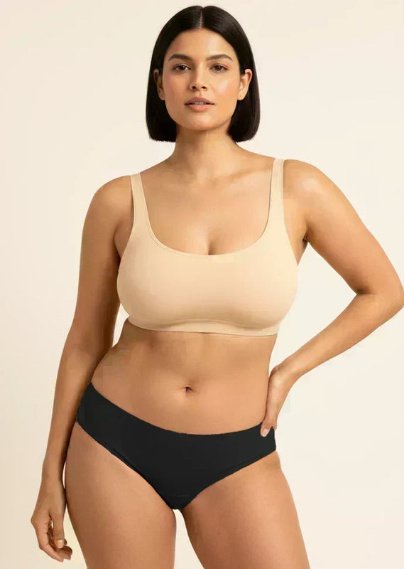 Woman wearing a beige bra and black underwear on a beige background
