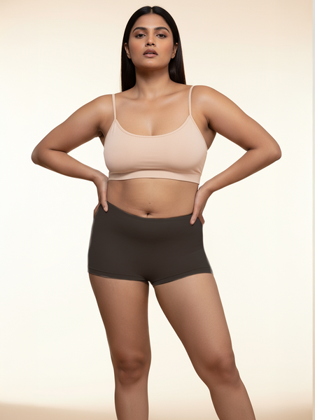 Woman wearing a beige bra and black boyshorts on a beige background