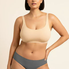 Woman wearing a beige bra and gray underwear on a beige background