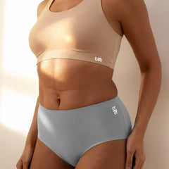 Person wearing a beige sports bra and grey mid-waist underwear with 'tilt' branding