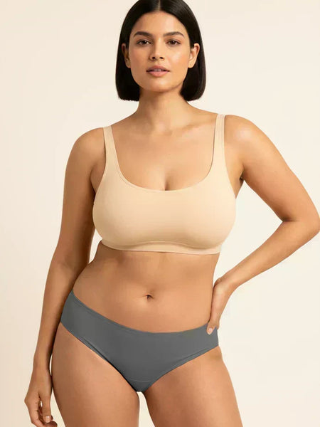 Woman wearing a beige bra and gray underwear on a beige background