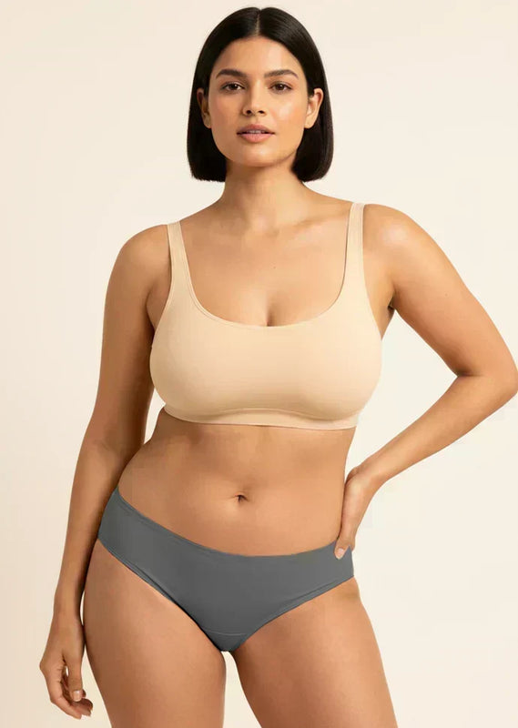 Woman wearing a beige bra and gray underwear on a beige background