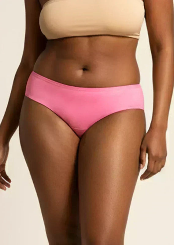 Person wearing pink low-waist underwear and beige bra on a neutral background