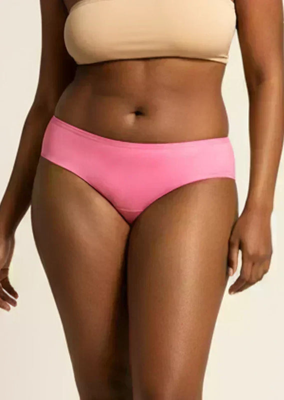 Person wearing pink low-waist underwear and beige bra on a neutral background