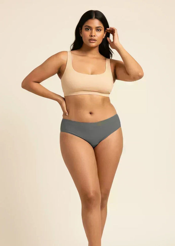 Woman wearing a beige sports bra and gray low-waist underwear on a beige background