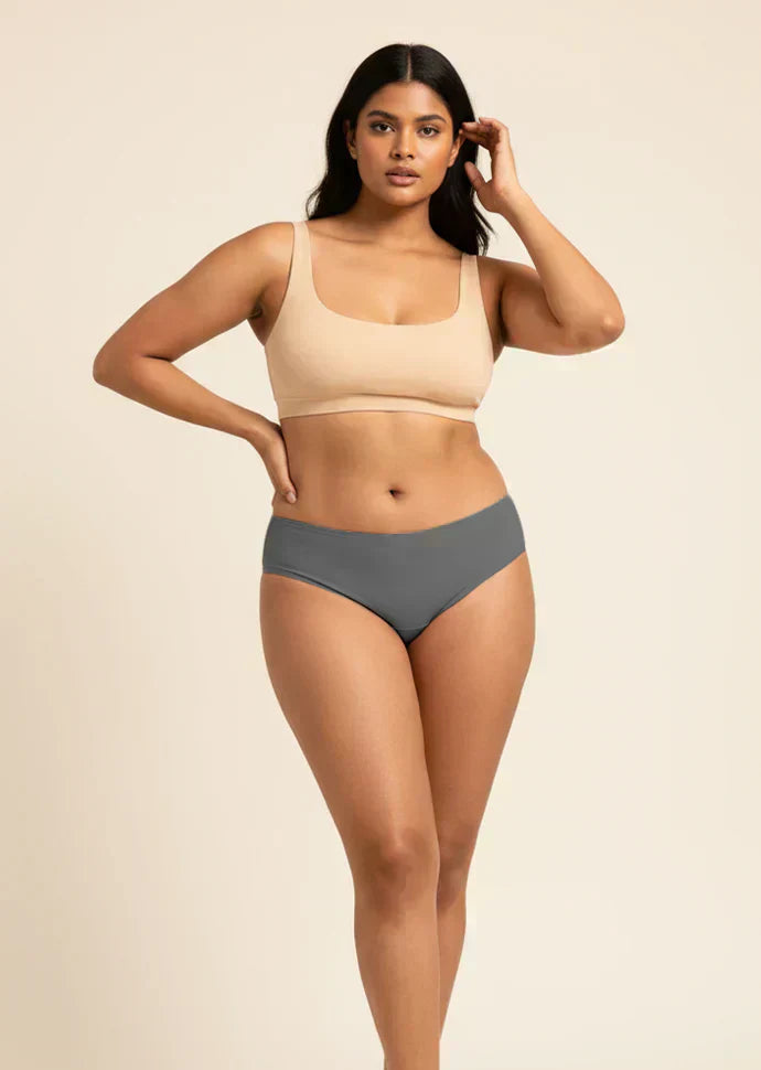 Woman wearing a beige sports bra and gray low-waist underwear on a beige background