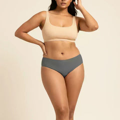 Woman wearing a beige sports bra and gray low-waist underwear on a beige background