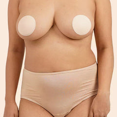 Person wearing beige silicone nipple covers on a plain background