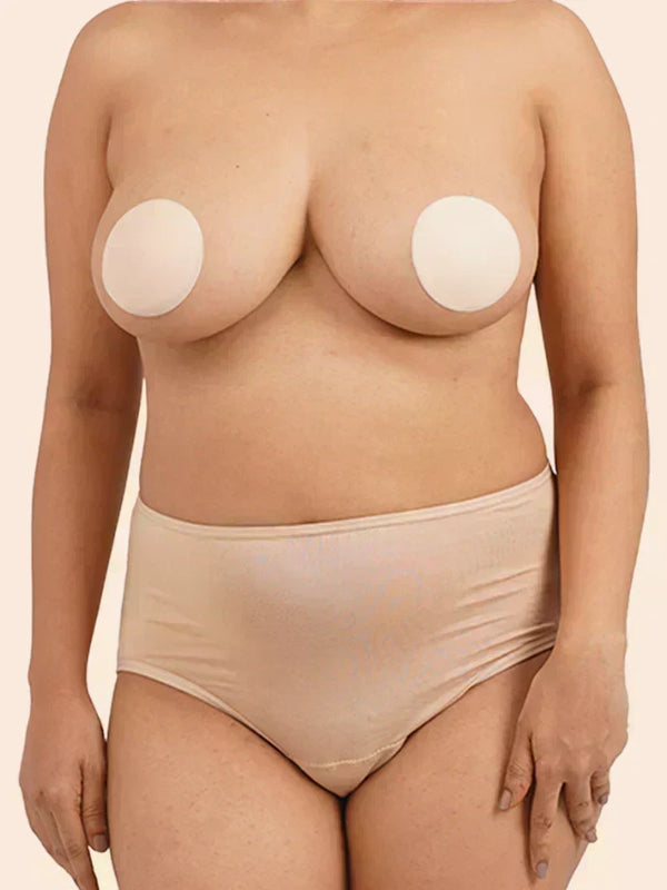 Person wearing beige silicone nipple covers on a plain background