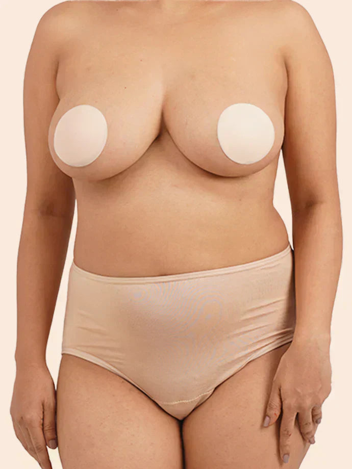 Person wearing beige silicone nipple covers on a plain background