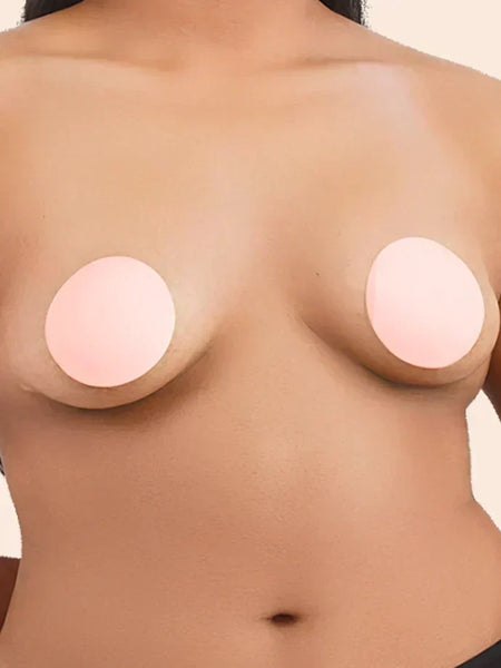 Close-up of a person wearing round, beige nipple covers