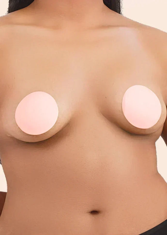 Close-up of a person wearing round, beige nipple covers
